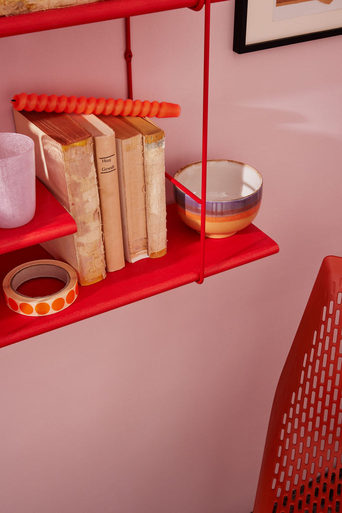 side view of a lobster shelf hanging on a pink wall with yellow and orange decoration on it